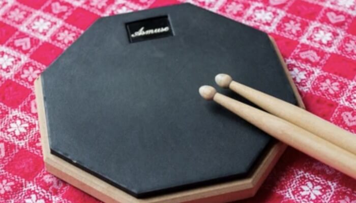 A black practice drum pad with drumsticks