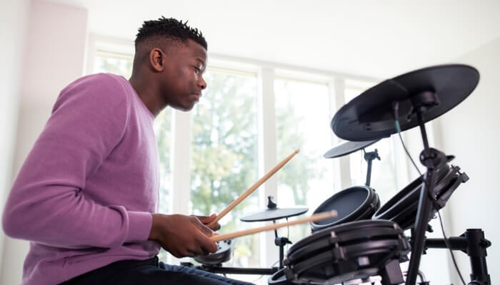 The eeenage boy is having fun drumming at home