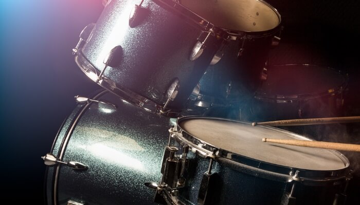 The man is playing percussion set in the low light background